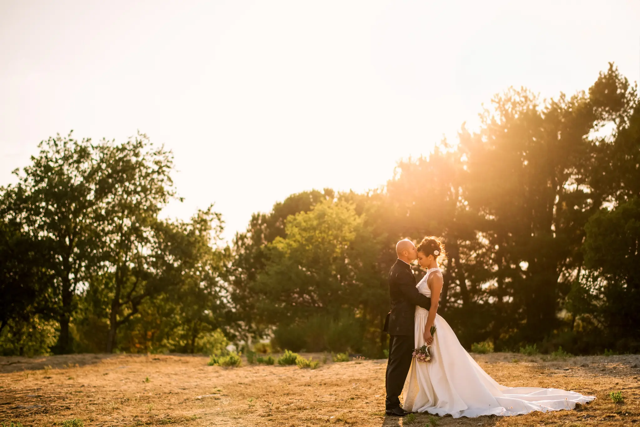 Hochzeitspaar küsst sich bei Sonnenuntergang